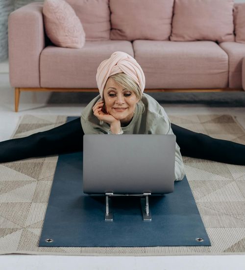 Person comfortably doing stretching exercises on a mat in their apartment.